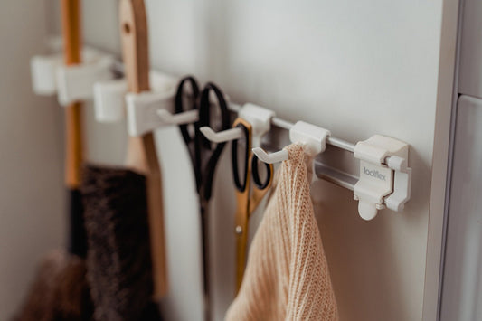 White utility hooks mounted on rail holding tools