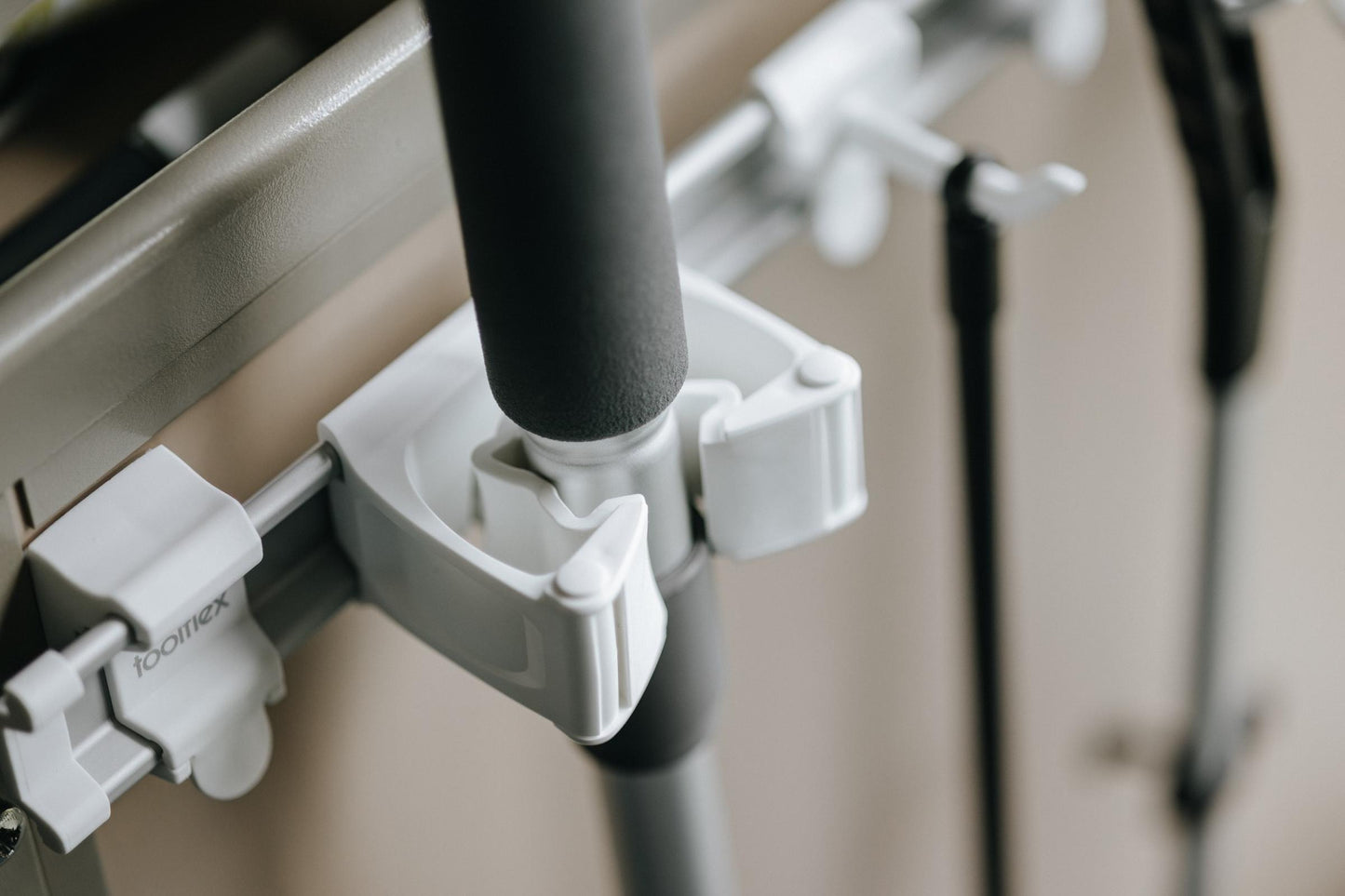 Toolflex One white holder close-up mounted on rail holding cleaning tool handle